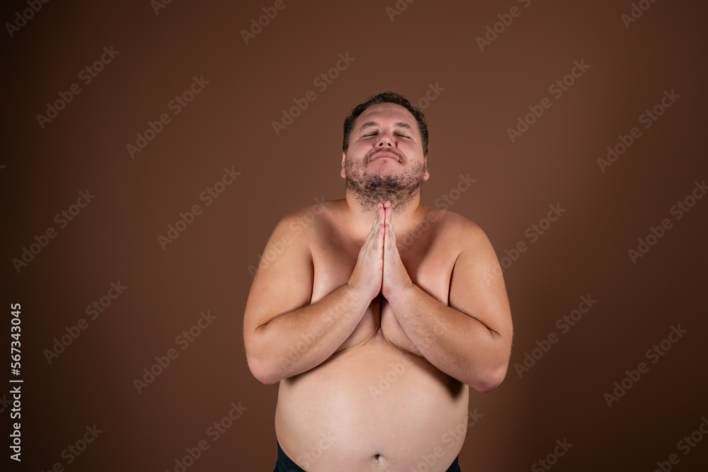Fototapeta premium A man gesticulates against the background in the studio. Greetings, hands to the side.