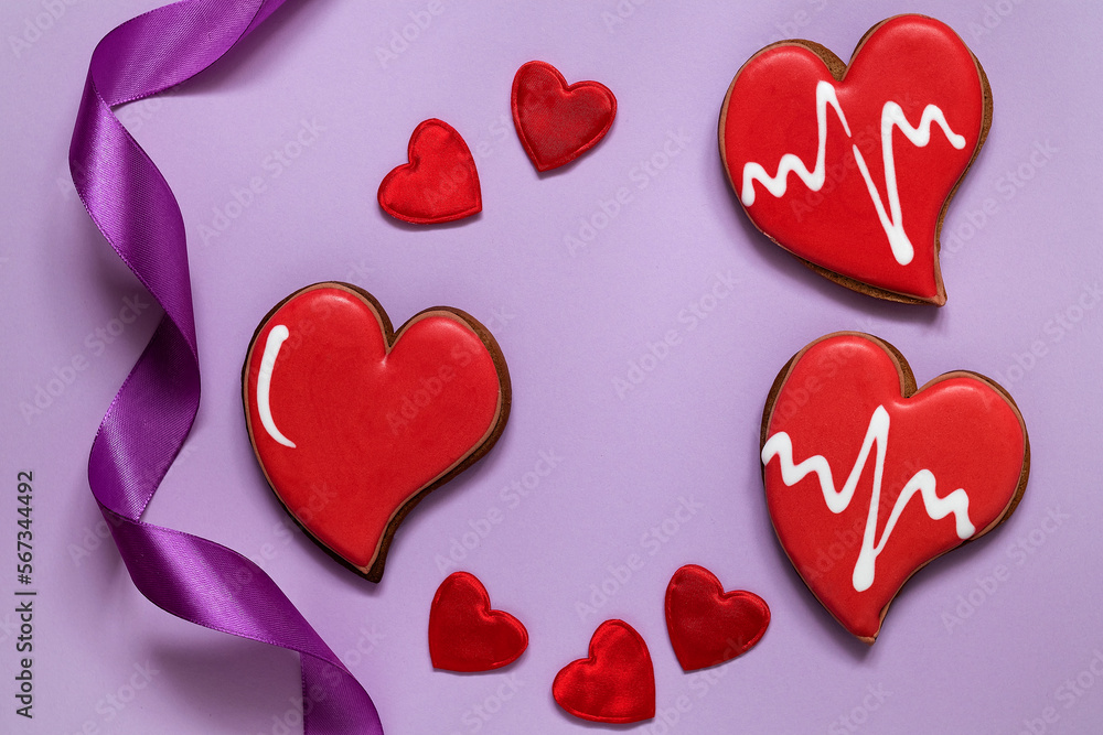 Red heart shaped cookies and satin ribbon on a purple background. Glazed cookies for Valentine's day. Love concept. Top view. Copy space. Red heart shaped cookies and satin ribbon on a purple background. Glazed cookies for Valentine's day. Love concept. Top view. Copy space.