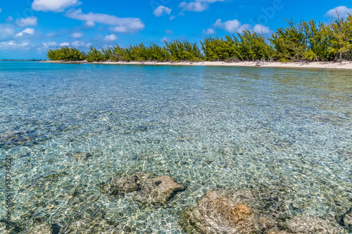 A view across crystal clear waters towards a deserted bay on the island of Eleuthera, Bahamas on a bright sunny day