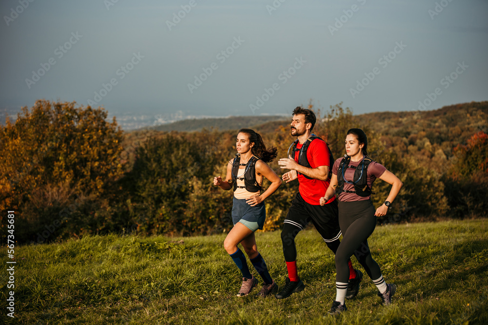 A diverse group of young people exercises outdoors, preparing for a mountain trail. They are wearing sports clothing and a trail running vest A diverse group of young people exercises outdoors, preparing for a mountain trail. They are wearing sports clothing and a trail running vest