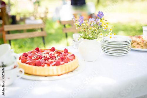 Familiennachmittag im Grünen mit  weißem Tischtuch , einem Blumensträußchen, Kaffee und Erdbeeertorte.