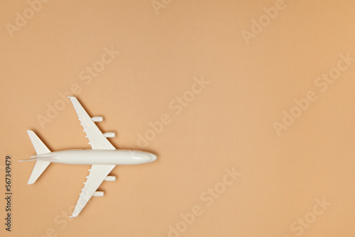 Airplane model. White plane on brown background. Travel vacation concept. Summer background. Flat lay, top view, copy space.