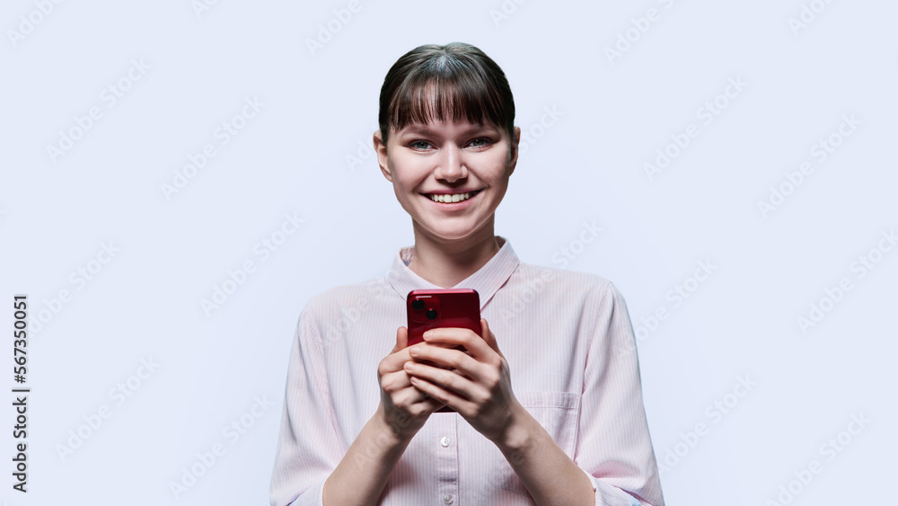 Young female with smartphone, looking at camera on white background Young female with smartphone, looking at camera on white background