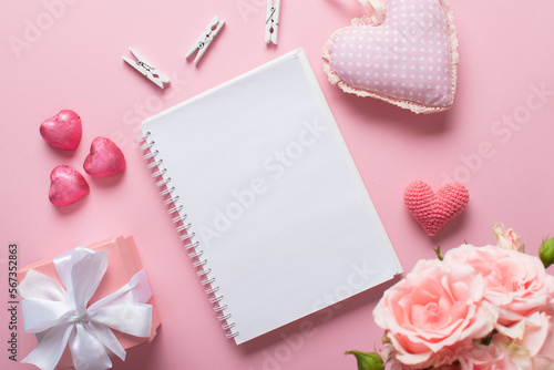 An open notebook with a gift and sweets on a light pink background. Valentine's day.