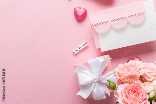 St. Valentine's Day banner with a bouquet of roses, a gift, candy on a light pink background. © Irina Lesovaia