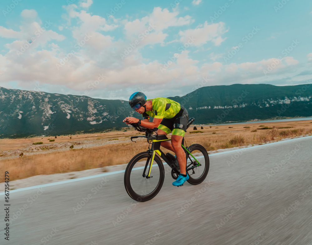 Fototapeta premium Full length portrait of an active triathlete in sportswear and with a protective helmet riding a bicycle. Selective focus 