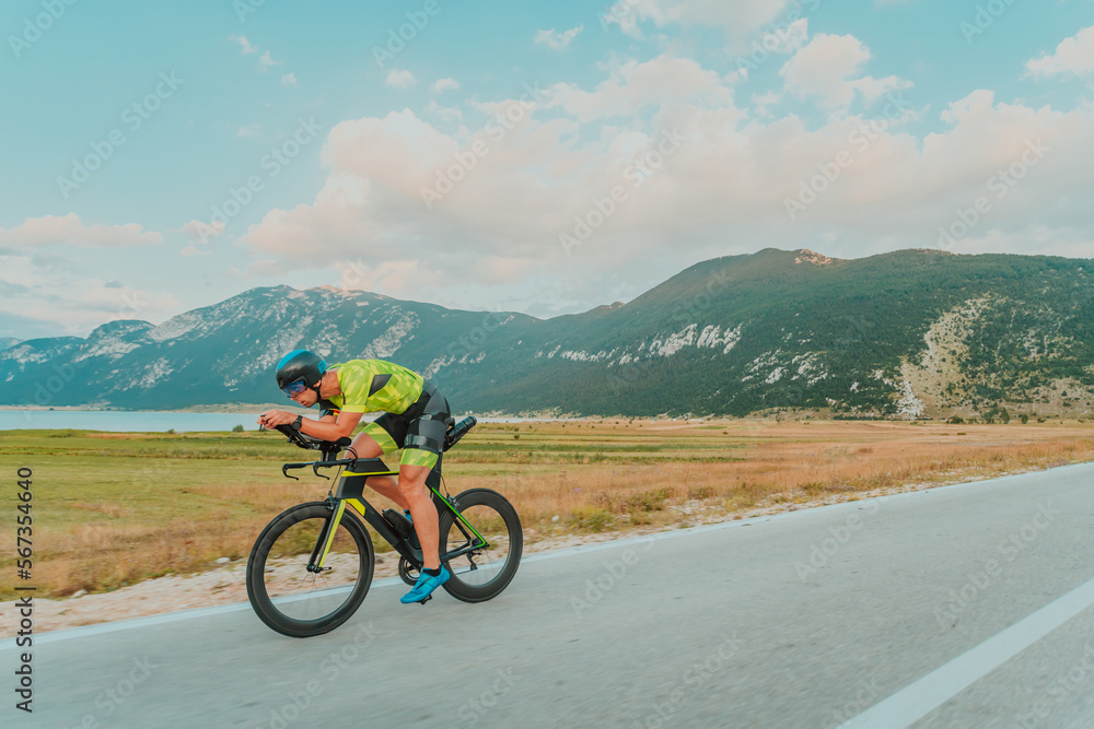 Full length portrait of an active triathlete in sportswear and with a protective helmet riding a bicycle. Selective focus 