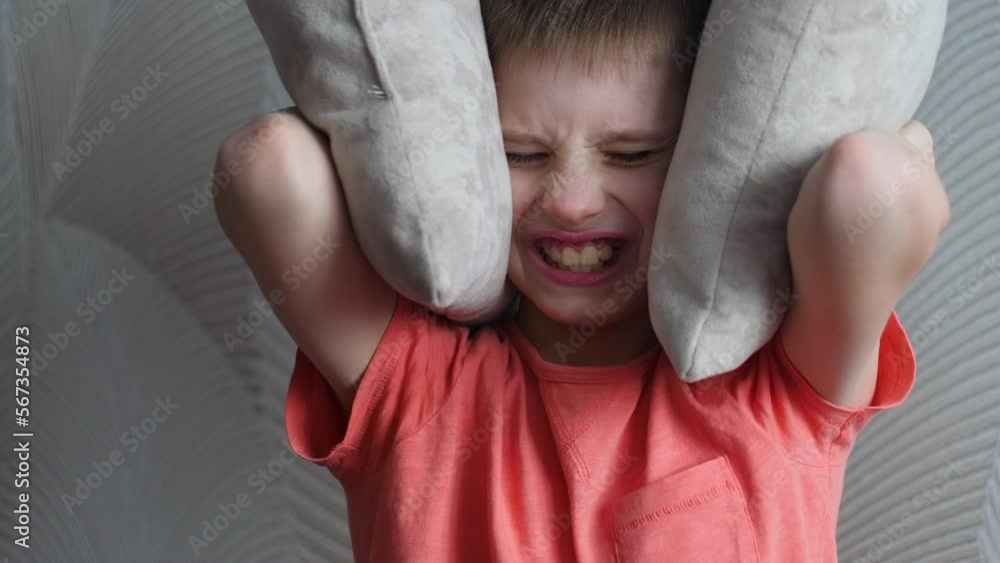 portrait of an angry caucasian boy 9 years old covering his ears with