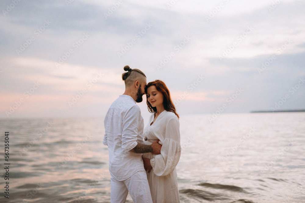 a guy with a girl in white clothes on the seashore