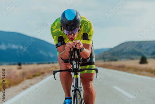 Full length portrait of an active triathlete in sportswear and with a protective helmet riding a bicycle. Selective focus 