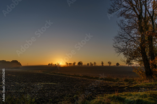 Beautiful sunrise over the mountains in the area of still shaded farmland