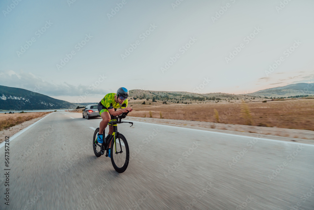 Full length portrait of an active triathlete in sportswear and with a protective helmet riding a bicycle. Selective focus Full length portrait of an active triathlete in sportswear and with a protective helmet riding a bicycle. Selective focus