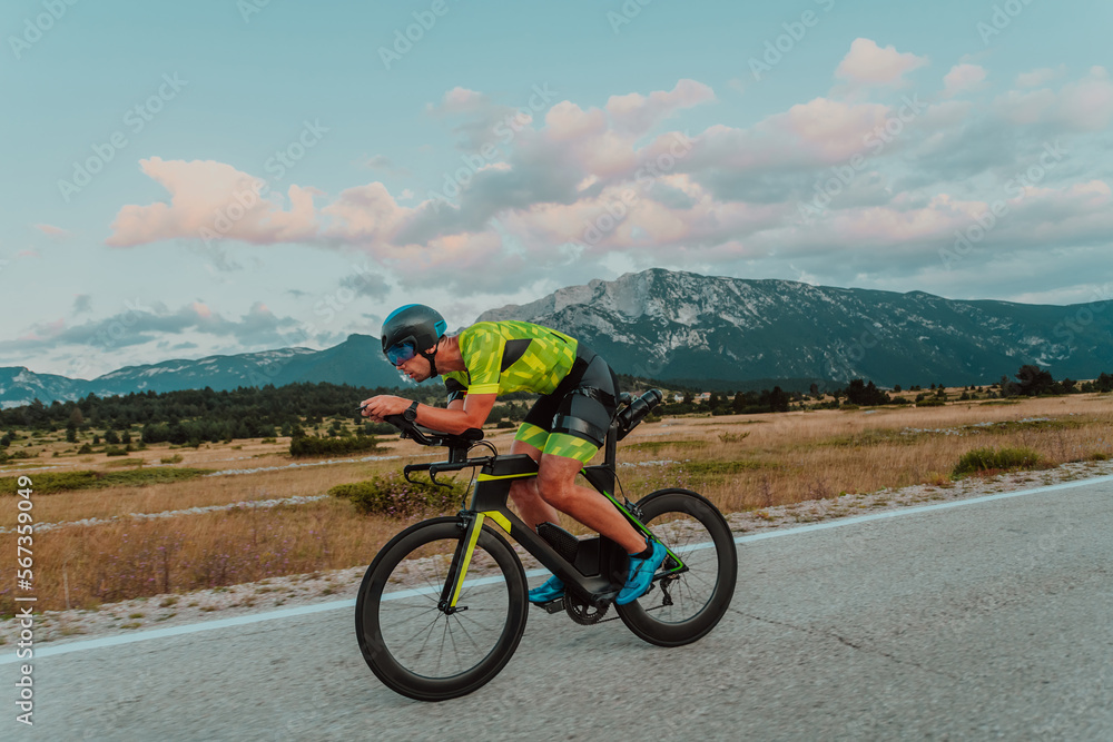 Full length portrait of an active triathlete in sportswear and with a protective helmet riding a bicycle. Selective focus Full length portrait of an active triathlete in sportswear and with a protective helmet riding a bicycle. Selective focus