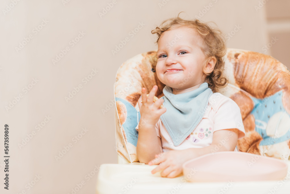 Happy little baby eats at home sitting on a chair Happy little baby eats at home sitting on a chair