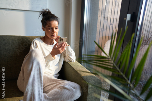 Mixed race woman sitting on sofa and using mobile phone photo