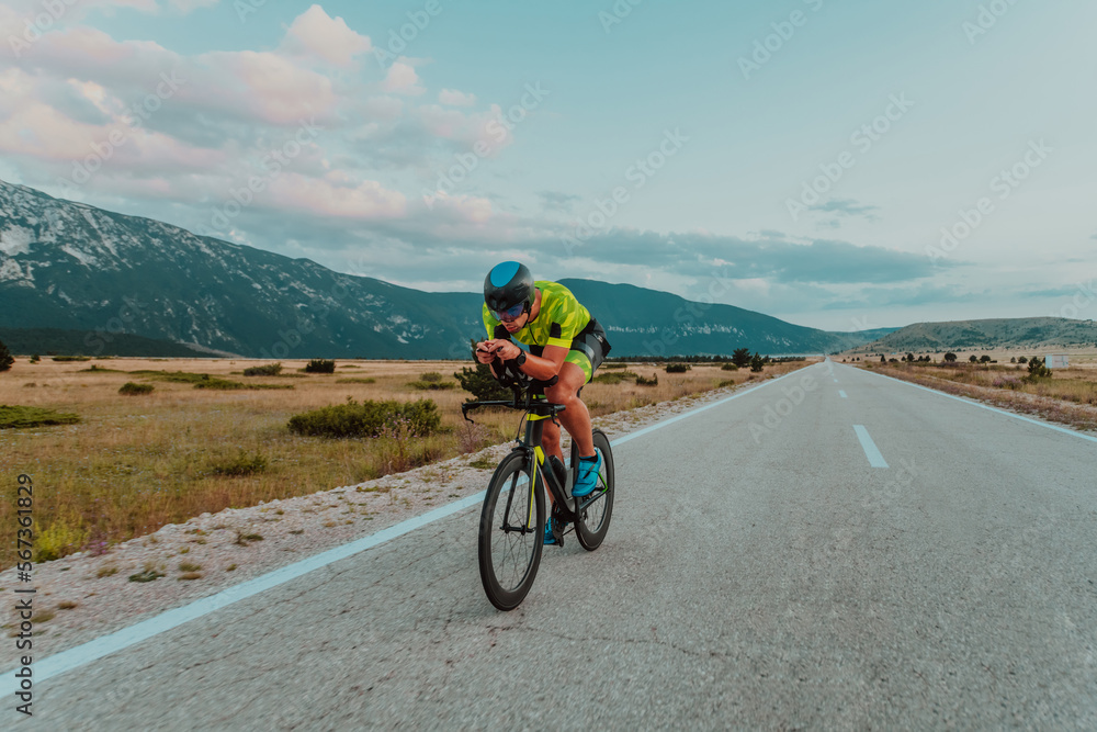 Full length portrait of an active triathlete in sportswear and with a protective helmet riding a bicycle. Selective focus 