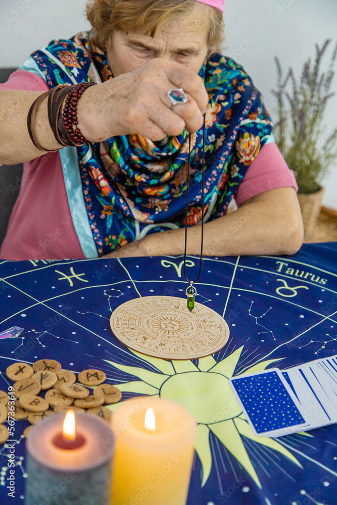 Fotografie Woman fortune teller fortune telling pendulum. Selective focus.