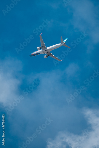 Airline plane over light blue sky with few clouds. Plane view in full takeoff.