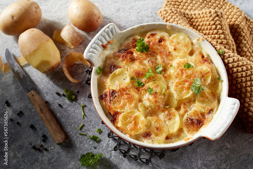 Hot delicious gratin potatoes with herbs in ceramic dish photo