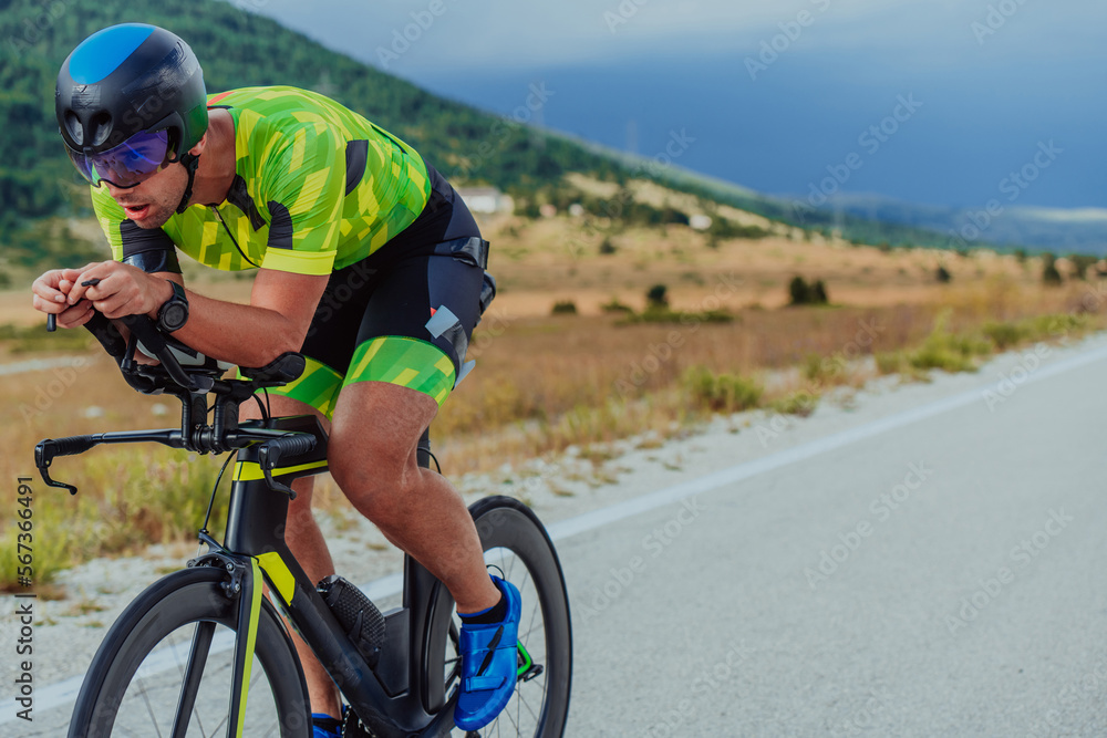 Full length portrait of an active triathlete in sportswear and with a protective helmet riding a bicycle. Selective focus Full length portrait of an active triathlete in sportswear and with a protective helmet riding a bicycle. Selective focus