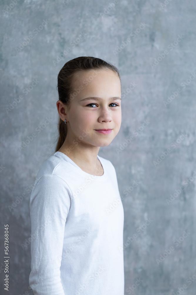 Selective focus vertical medium portrait of cute smiling blond little girl with concrete background