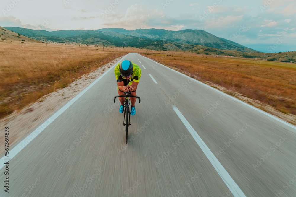 Full length portrait of an active triathlete in sportswear and with a protective helmet riding a bicycle. Selective focus Full length portrait of an active triathlete in sportswear and with a protective helmet riding a bicycle. Selective focus