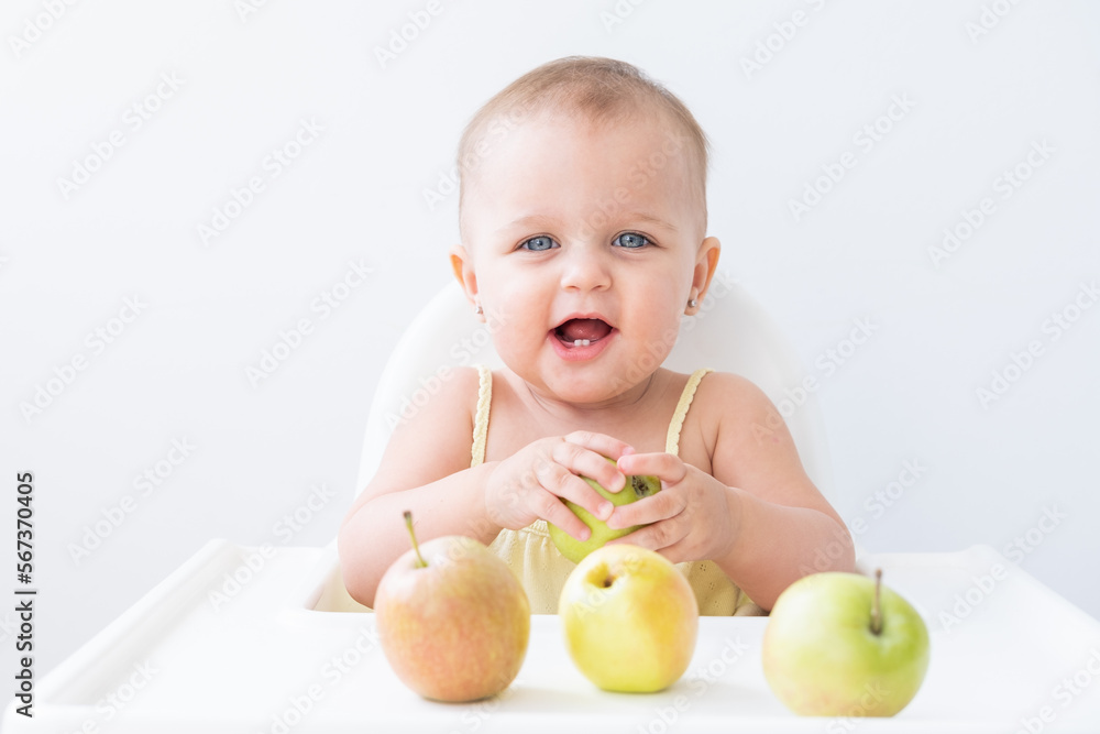 cute baby girl in baby chair eating apples. Baby first solid food cute baby girl in baby chair eating apples. Baby first solid food