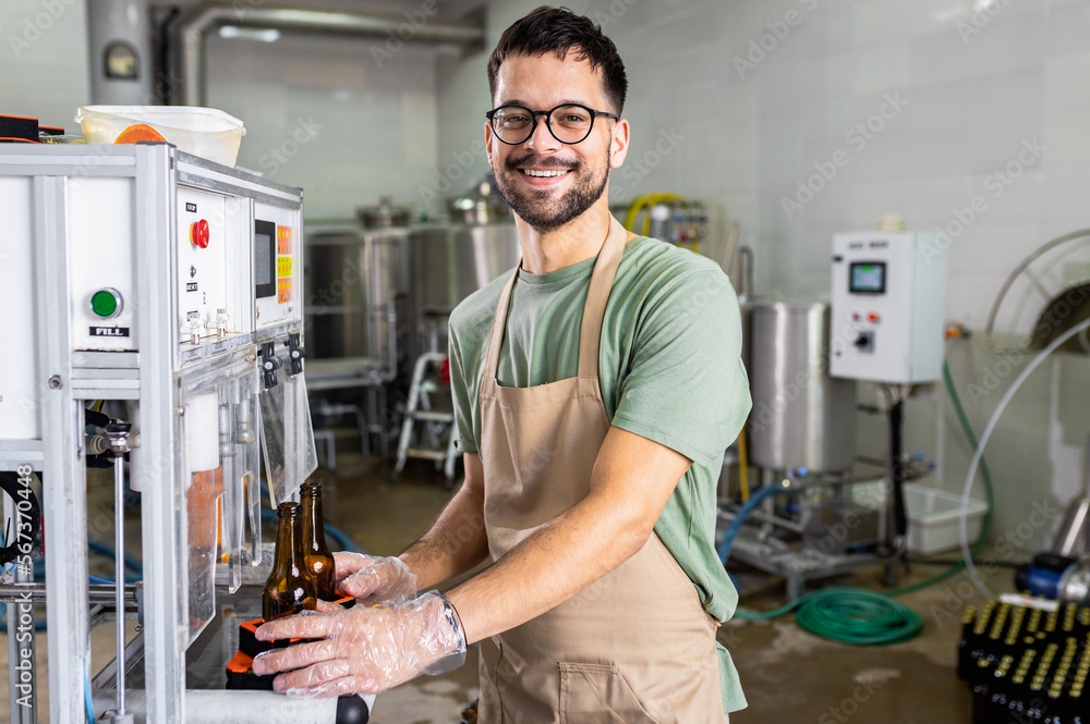 Male brewer working in a brewery filling bottles with beer. Male brewer working in a brewery filling bottles with beer.