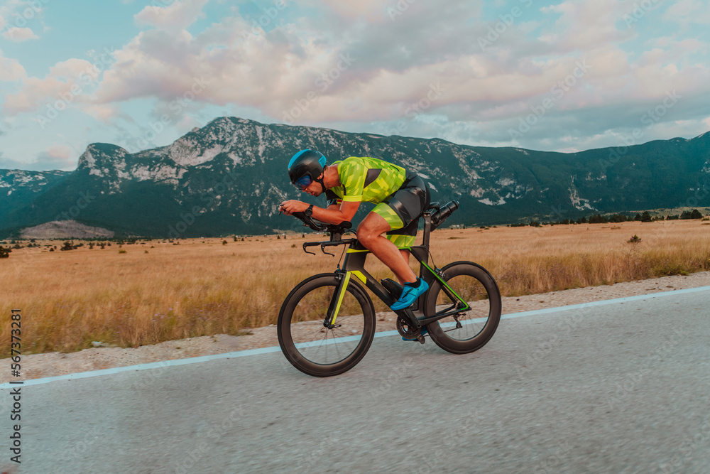 Obraz premium Full length portrait of an active triathlete in sportswear and with a protective helmet riding a bicycle. Selective focus 