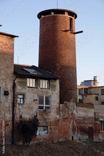 Abandoned old industrial area with tower and partially damaged buildings.
