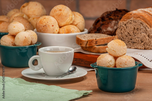 Cheese breads in a green ramekin with a cup of coffee on wooden table and bricks wall background.