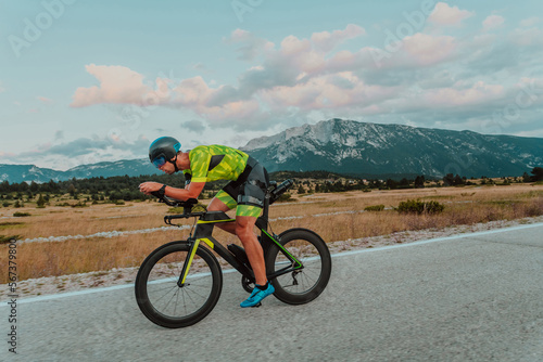 Full length portrait of an active triathlete in sportswear and with a protective helmet riding a bicycle. Selective focus 