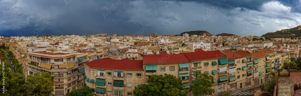 Top view of a densely built city with dark clouds in the background