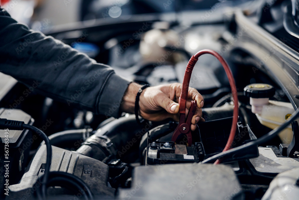 Close up of a worker's hand doing battery diagnostics at mechanic's shop. Close up of a worker's hand doing battery diagnostics at mechanic's shop.
