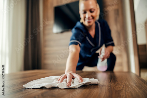 Close up of a maid cleaning floor with cloth and detergent in a hotel room. photo