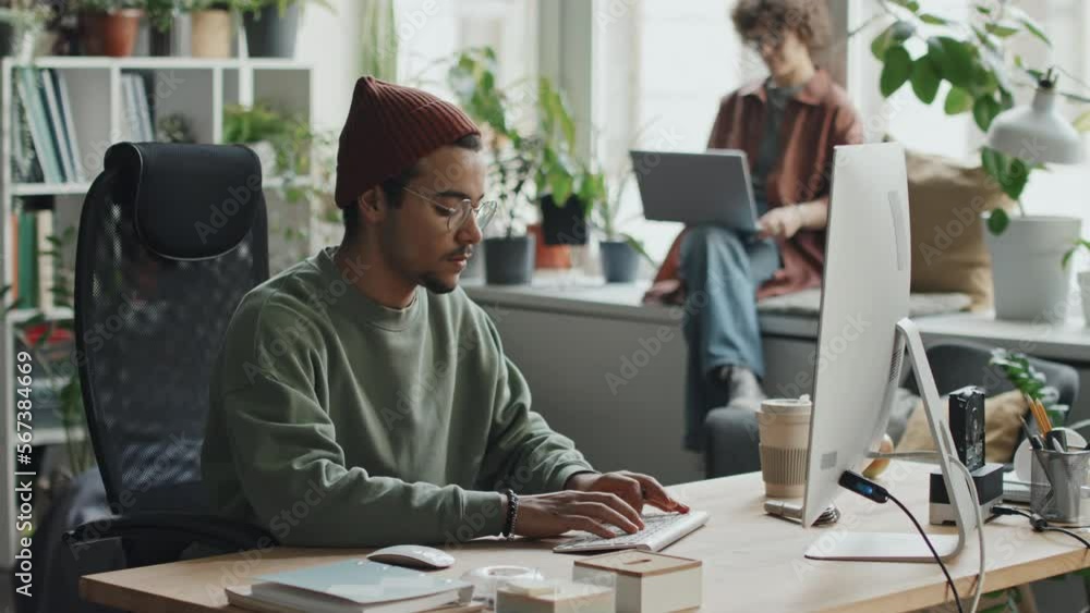 Young developer sitting at his workplace in front of computer monitor and working with computer program Young developer sitting at his workplace in front of computer monitor and working with computer program