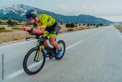 Full length portrait of an active triathlete in sportswear and with a protective helmet riding a bicycle. Selective focus 