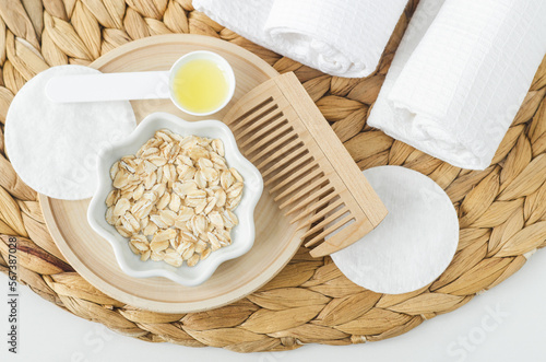 Small bowl with rolled oats and wooden hairbrush. Homemade hair or face mask, natural beauty treatment and spa recipe. Top view, copy space.