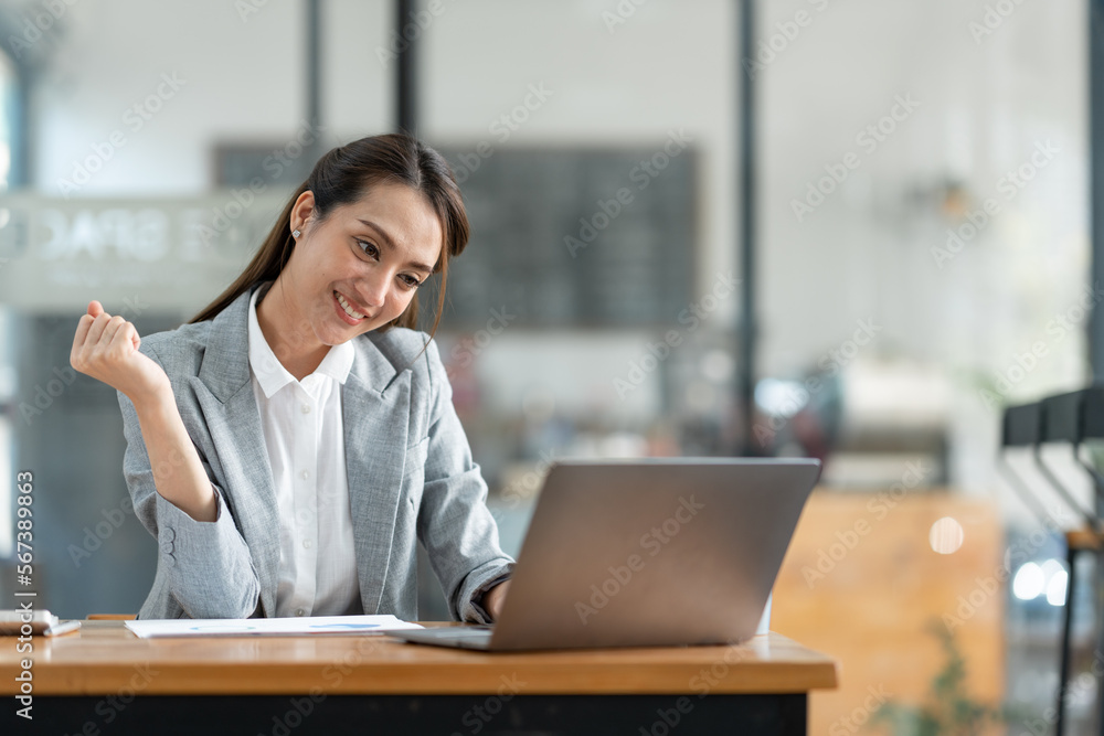 Asian businesswoman raising her hand with a happy expression to receive an email informing her about her annual bonus. concept of success. Asian businesswoman raising her hand with a happy expression to receive an email informing her about her annual bonus. concept of success.