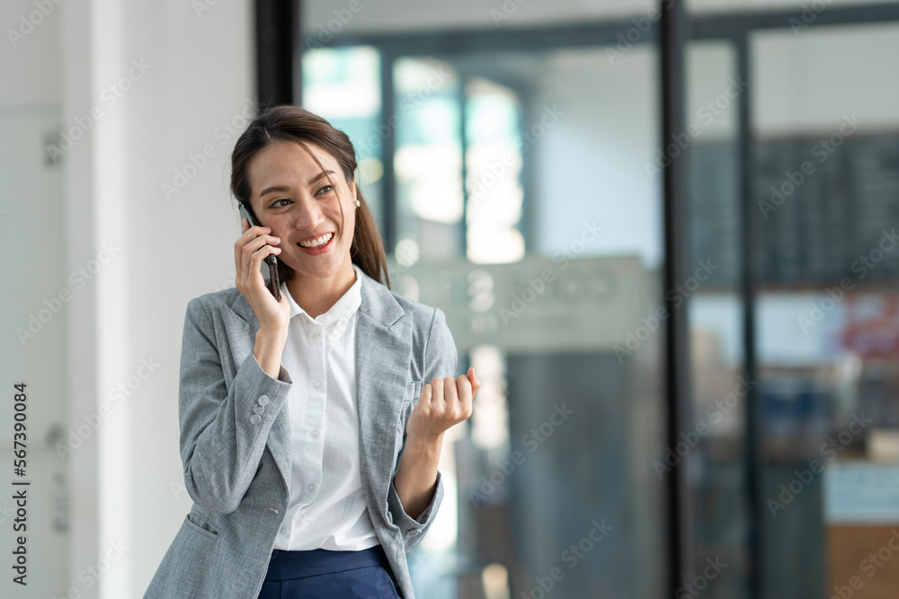 Attractive Asian businesswoman standing on the phone talking about real estate projects and chatting with happy smiles at the office. Attractive Asian businesswoman standing on the phone talking about real estate projects and chatting with happy smiles at the office.