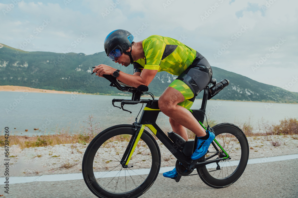 Full length portrait of an active triathlete in sportswear and with a protective helmet riding a bicycle. Selective focus Full length portrait of an active triathlete in sportswear and with a protective helmet riding a bicycle. Selective focus