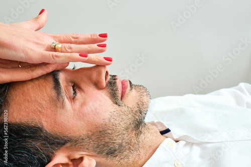 Fototapeta Naklejka Na Ścianę i Meble -  pretty woman's hands giving a face massage to a dark-haired man with a short beard