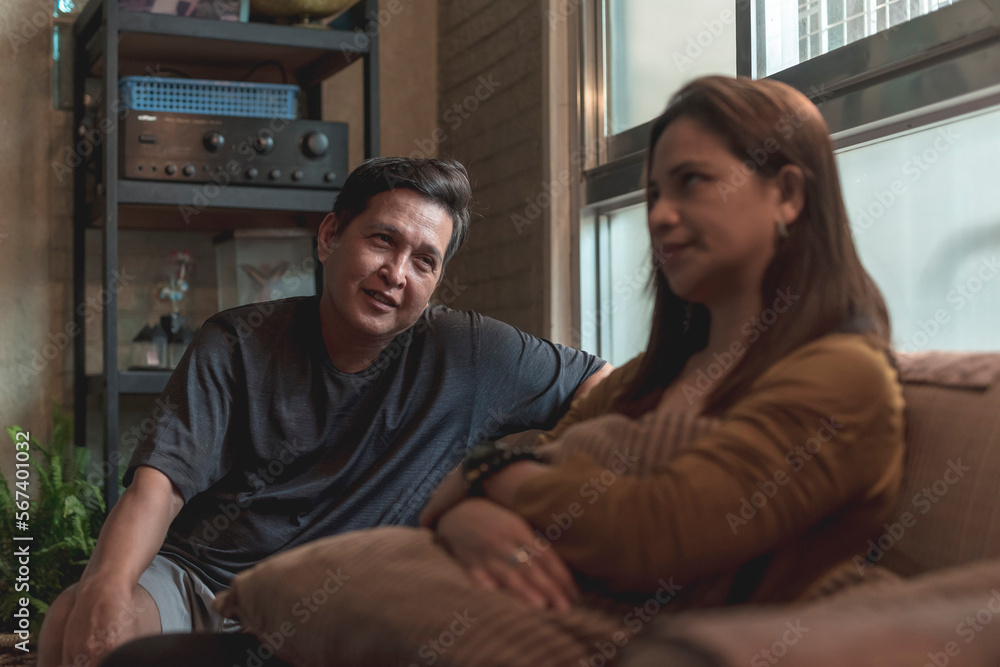 An asian woman is annoyed at her patronizing husband lecturing her on something while sitting on the couch. Classic example of mansplaining. An asian woman is annoyed at her patronizing husband lecturing her on something while sitting on the couch. Classic example of mansplaining.