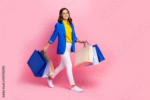 Full length profile photo of nice positive person hold bags walk isolated on pink color background