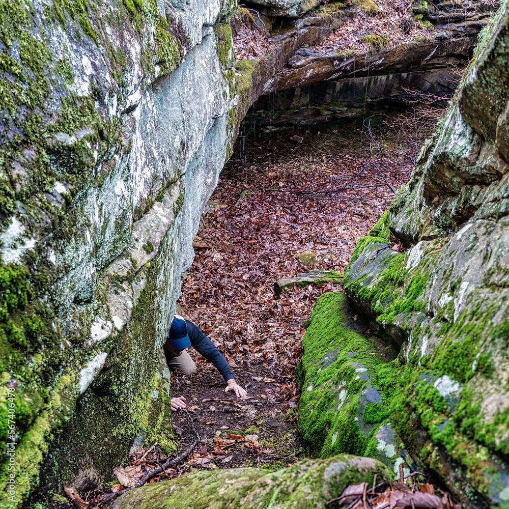 A man crawling from a cave in the Tennessee Mountains A man crawling from a cave in the Tennessee Mountains