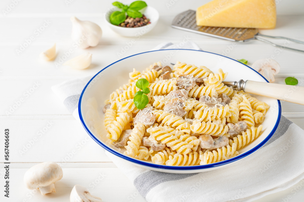 Fusilli pasta with mushrooms, cheese and fresh basil in a plate on a white wooden background. Fusilli pasta with mushrooms, cheese and fresh basil in a plate on a white wooden background.