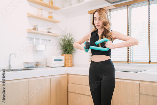motivated pretty woman pushing exercise tool in kitchen. gorgeous exerciser exercising exercise tool for muscle indoors. beautiful woman training home fitness holding equipment for healthy arm muscle