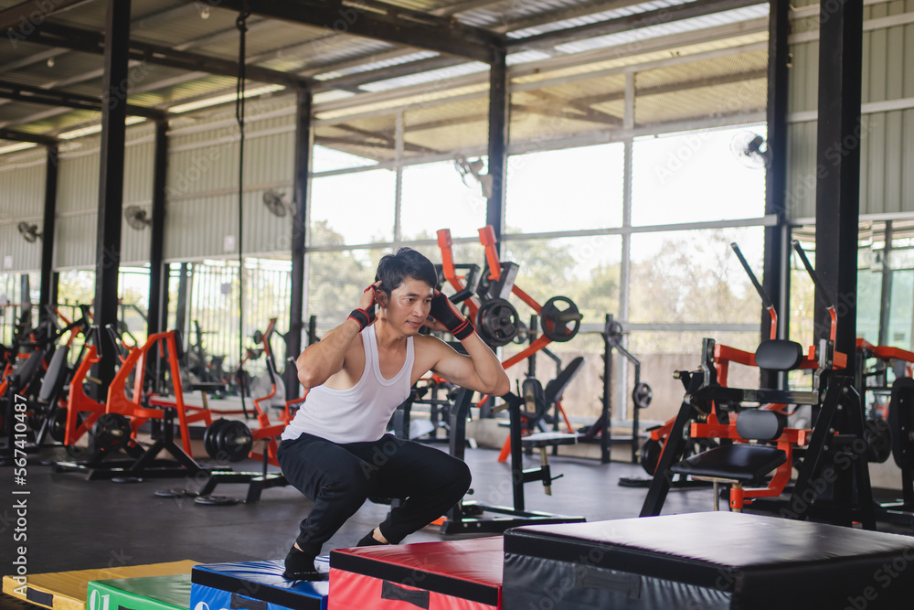 Man athletes exercising jump on crates during gym training in the gym