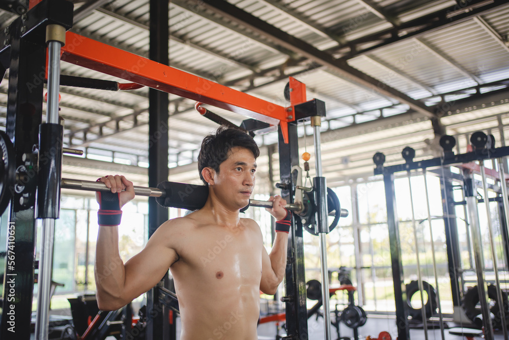 Man doing squat exercises with a barbell in gym Man doing squat exercises with a barbell in gym