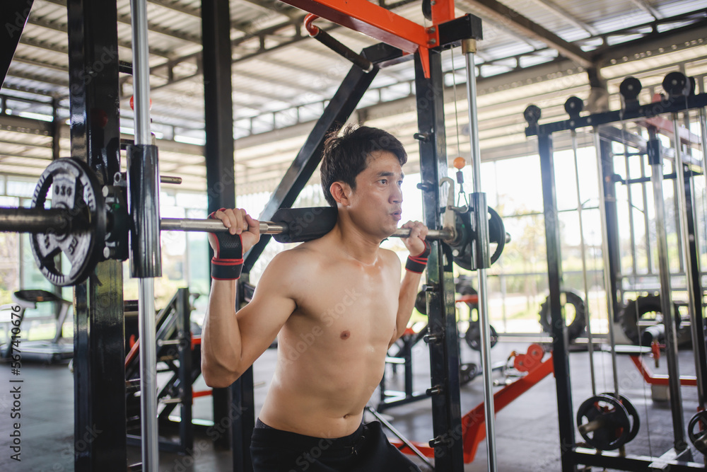 Man doing squat exercises with a barbell in gym Man doing squat exercises with a barbell in gym